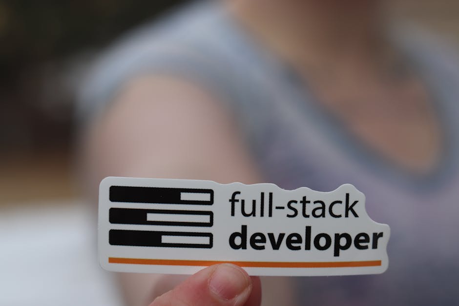 A close-up image shows a person holding a small, rectangular sticker in the foreground, which features a stylized black and white Wi-Fi signal icon alongside the words 'full-stack developer' in bold b